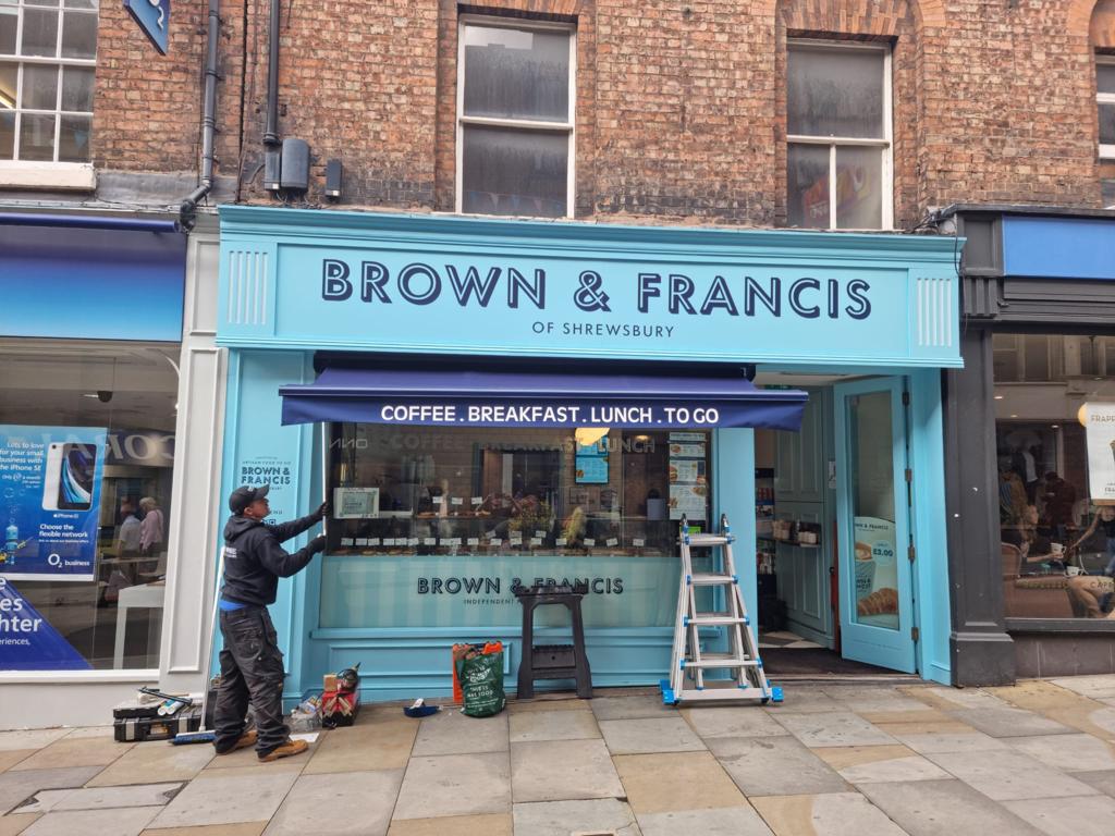 Blue awning being installed at a shop