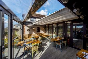 A retractable pergola at the back of a restaurant with a sunny sky